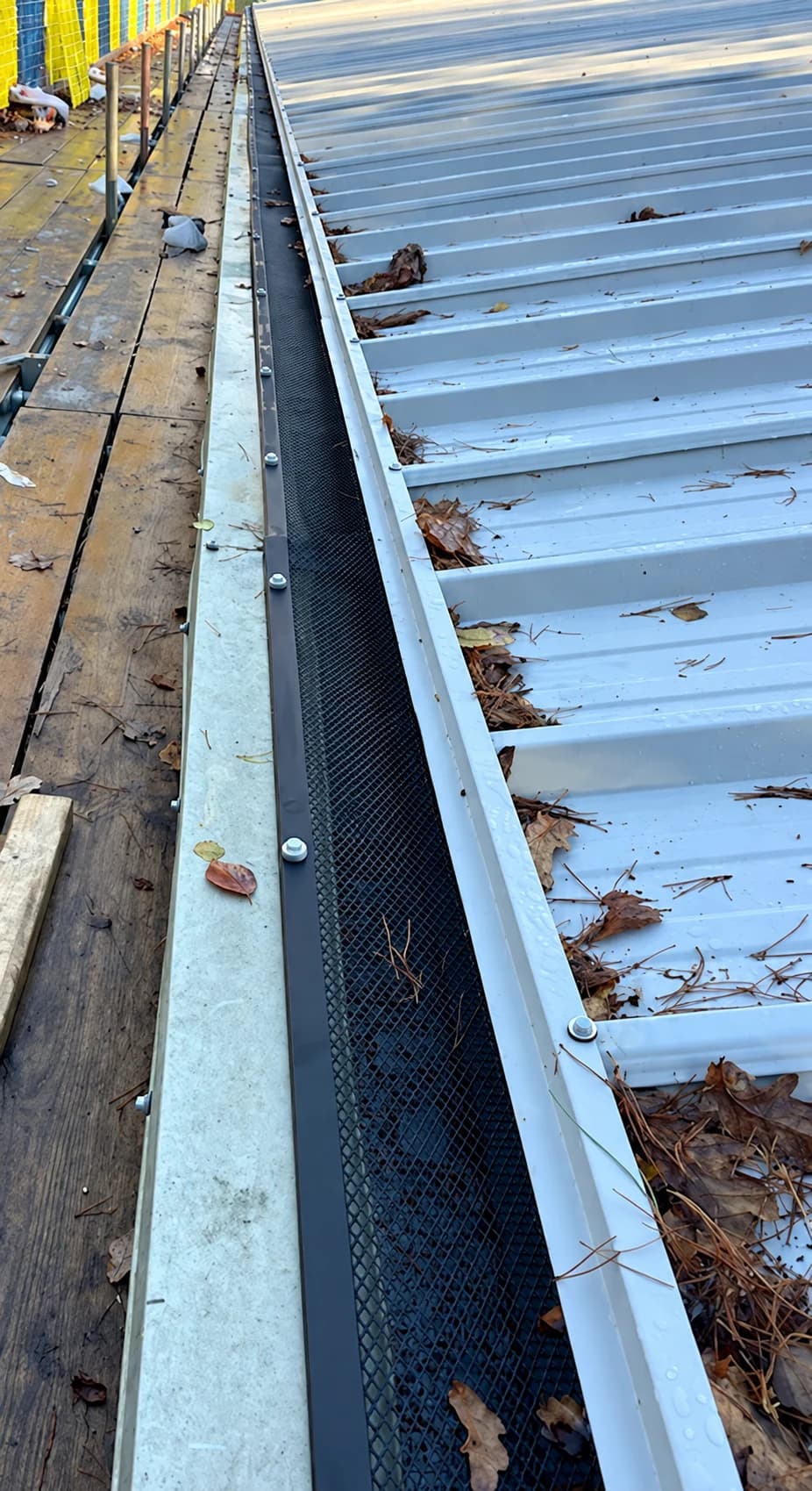 Custom leaf guard and galvanised gutter channel installed beside the metal roof